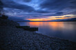© juraj - Old fishing boats on a gravel beach under a colorful sky at dusk
