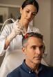 © W.O.W - Woman doctor using laser treatment on mans scalp for hair growth. Medical procedure for hair restoration and health. Dermatology and cosmetology concept.
