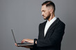 © SHOTPRIME STUDIO - A professional man works on a laptop against a solid colored background, projecting focus and calm. He conveys confidence and thoughtful purpose in a business portrait.