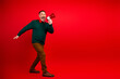 © deagreez - Cheerful man with megaphone dancing in red studio spreads Christmas joy for shoppers