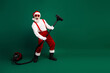 © deagreez - Santa Claus having fun vacuuming with festive spirit against a green background, dressed in red and white traditional costume