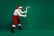 © deagreez - Santa Claus wearing a funky Christmas costume holds an axe playfully on a green background, embodying a unique and fun holiday spirit.