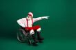 © deagreez - Festive Santa Claus in a wheelchair spreading joy and cheer in a vibrant green studio for a merry holiday season