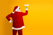 © deagreez - Santa Claus painting a yellow wall with a roller while wearing his traditional red Christmas attire in a vibrant scene