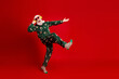 © deagreez - Santa in green pajama with reindeer print dances on red background wearing striped socks for Christmas fun