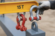 © newlifestock - Crane safety is ensured by securely attaching heavy duty shackles to yellow lifting beam rated for 15 tons with gloved hand handling equipment