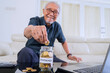 © Creativa Images - Happy Senior Man Saving Coins in a Jar Labeled 'Emergency' for Retirement Planning