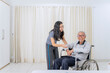 © Creativa Images - Caring Young Woman Smiling While Assisting a Happy Senior Man in a Wheelchair at Home