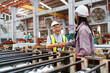 © DG PhotoStock - Senior engineer and factory worker shaking hands in factory, showing teamwork success.
