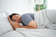 © Kawee - Asian plus-size woman in pajamas sleeping in the morning with happiness