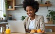 © Susan - Smiling young woman using laptop while having breakfast at home kitchen. High quality