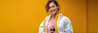 © Iryna - Young asian female smiling in athletic wear holding a drink against yellow background