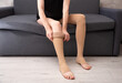 © Paulina_OK - Female model wearing compression socks sitting on grey sofa indoors demonstrating healthy lifestyle, vein care and prevention of venous disease