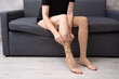 © Paulina_OK - Female model wearing compression socks sitting on grey sofa indoors demonstrating healthy lifestyle, vein care and prevention of venous disease