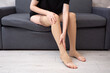 © Paulina_OK - Faceless female wearing compression socks sitting on grey sofa indoors demonstrating healthy lifestyle, vein care and prevention of venous disease