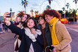 © Xavier Lorenzo - Young happy diverse group in winter clothes taking selfie portrait outdoors. Youth and friendship concept