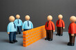 © Andrii Yalanskyi - A brick wall separates two ideological camps of office workers. Two opposing teams or business departments. Competition, team disagreement, or workplace polarization.