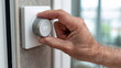 © Alive - Adjusting the thermostat in a modern home during warm weather
