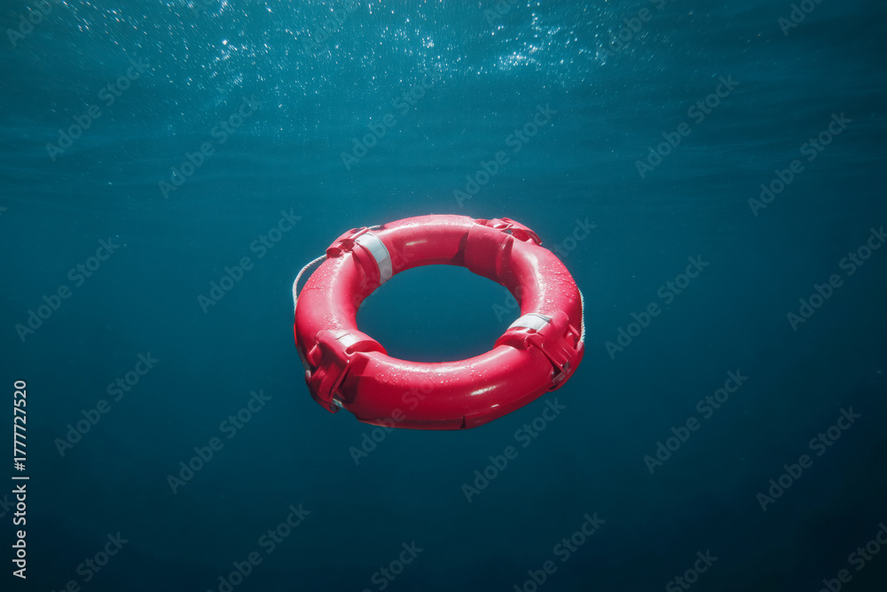 Bright red life preserver floats in deep blue ocean water, symbolizing hope and rescue