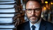 © No PEOPLe - professional businessman with glasses and beard surrounded by stacks of documents in office environment
