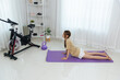 © sorapop - Young woman home activity, happy person performs yoga pose on mat, enjoying fitness exercise for wellness, promoting healthy lifestyle, surrounded by personal workout equipment.