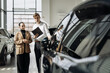 © wedmoments.stock - Sales representative engaging with a customer in a modern car dealership, showcasing vehicles and providing information about car features and financing options