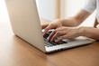 © hidez - Woman typing on laptop at a wooden desk