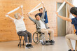 © buritora - Senior men and women doing exercises and stretching at a nursing home, day care center, and staff