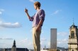 © Studio Sincère/Stocksy - Man Taking Photo on Rooftop With Brussels Skyline Under Blue Sky
