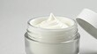 © saranya - Macro closeup of a luxurious white cosmetic cream with a perfect swirl peak in an open glass jar, showing texture and purity on a clean, bright background.
