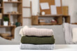 © Pixel-Shot - Stack of stylish winter sweaters on table in living room