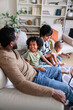 © Jovo Jovanovic/Stocksy - Family relaxes together on a couch in a living room.