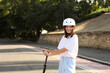 © Pixel-Shot - Happy young woman in helmet riding electric kick scooter outdoors