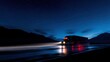 © Sergey - diesel truck driving on a mountain highway at night, headlights and taillights glowing brightly, light trails on wet asphalt, starry sky above dark