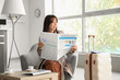 © Pixel-Shot - Young Asian woman reading newspaper in airport lounge