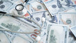© Jokiewalker - Close up stethoscope on hundred dollar bills symbolizing rising medical fees, expensive treatment payments and healthcare financial pressure.