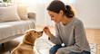 © Iryna - Woman giving dog a treat in living room, pet care and training at home
