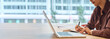© Stock 4 You - Closeup impersonal young business woman working on laptop computer at office desk with city view. Manager businesswoman or female student using pc for work, learning at workplace. Banner, copy space