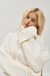 © LIGHTFIELD STUDIOS - Beautiful young blonde woman poses in cozy knitted sweater in studio setting