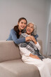 © Pichsakul - Asian women generations showing affection bonding with smiles warm embrace cozy home living room setting intergenerational care love family support