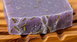 © Platon - Handmade Natural Lavender Soap Bar on a Warm Wooden Soap DishA detailed, close-up shot of a rectangular bar of natural, handmade soap resting on a grooved wooden soap dish