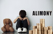 © New Africa - Sad little boy and toy near wall and stacked coins. Alimony, money support for child after divorce