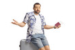 © Ljupco Smokovski - Male tourist holding a passport and sitting on a suitcase
