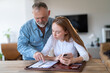 © Iryna - Two people discussing plans at a kitchen table while reviewing documents and using a smartphone in a bright, modern home setting