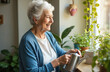 © miss irine - Grey-haired elderly woman smiles happily, waters thriving green houseplants by sunny window in bright apartment. Senior lady enjoys daily home gardening hobby, caring for nature indoors. Old female