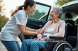 © miss irine - Asian caregiver assists elderly woman in wheelchair next to open car. Both women share happy smiles, enjoying pleasant conversation outdoors. Younger person offers support for senior lady, helping