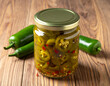© Yopei Apriliansyah - A jar of pickled jalapeno pepper. Isolated on a wooden background.