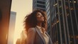 © Studicon - A successful businesswoman smiles, looking up at city skyscrapers during a golden hour sunset