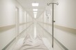 © Jelena - Patient viewpoint down bright hospital corridor with IV drip soft blur caring atmosphere