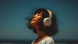 © Anuson - A young woman with eyes closed enjoying music with wireless headphones and the ocean breeze in summer air.